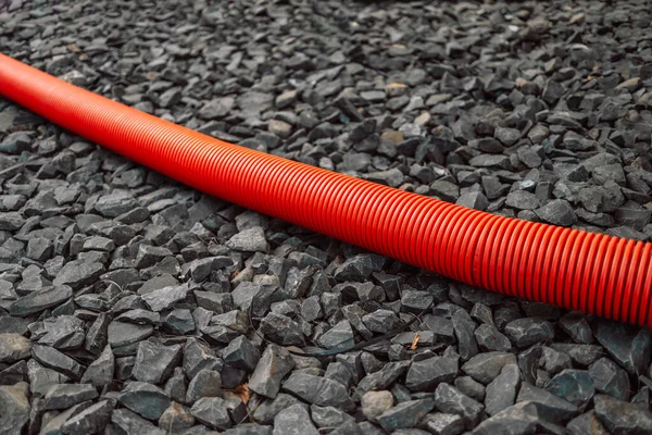 Plastic pipe for underground utilities of red color lie on a ground.
