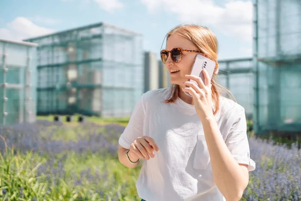 Happy smile blonde woman talking with somebody on mobile phone while walking in front of Museum