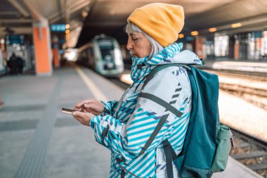 Güneş ışığı peronunda cep telefonu tutan kadın. Teknoloji akıllı telefonu çevrimiçi bağla. Bayan seyahat treni alet cep telefonu kullanıyor. Dijital Wi-Fi internet yaşam tarzı modeli. 