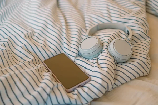 Morning time. Headphone and phone on bed.