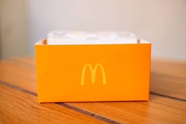 McDonalds Restoranı 'ndaki masada üzerinde McDonalds logosu olan sarı kağıt kutu. Krakow, Polonya - 25 Ağustos 2022 