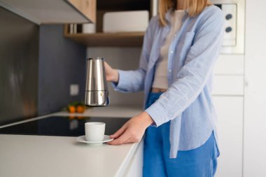 Çekici bir kadın mutfakta bir bardak sıcak kahveyi camdan dolduruyor. Sabahları kahvaltı ediyorum.. 