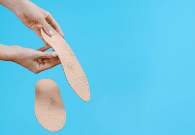 Mavi bir arkaplanda ortopedik insole izole edildi. Tıbbi tabanlar. Düz taban ve ayak hastalıklarının tedavisi ve önlenmesi. Ayak bakımı, ayak rahatlığı. Rahat ayakkabılar giy. Düz Ayak Düzeltme