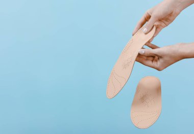 Mavi bir arkaplanda ortopedik insole izole edildi. Tıbbi tabanlar. Düz taban ve ayak hastalıklarının tedavisi ve önlenmesi. Ayak bakımı, ayak rahatlığı. Rahat ayakkabılar giy. Düz Ayak Düzeltme