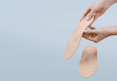 Mavi bir arkaplanda ortopedik insole izole edildi. Tıbbi tabanlar. Düz taban ve ayak hastalıklarının tedavisi ve önlenmesi. Ayak bakımı, ayak rahatlığı. Rahat ayakkabılar giy. Düz Ayak Düzeltme