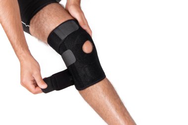 Diz Destek Kolu beyaz arka planda izole edilmiş bir bacak üzerinde. Ortopedik Anatomik. Diz sabitleme, yaralanma ve ağrı için diş telleri. Diz eklemi bandaj kolu. Elastik Spor