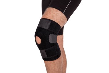 Diz Destek Kolu beyaz arka planda izole edilmiş bir bacak üzerinde. Ortopedik Anatomik. Diz sabitleme, yaralanma ve ağrı için diş telleri. Diz eklemi bandaj kolu. Elastik Spor
