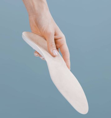Mavi bir arkaplanda ortopedik insole izole edildi. Tıbbi tabanlar. Düz taban ve ayak hastalıklarının tedavisi ve önlenmesi. Ayak bakımı, ayak rahatlığı. Rahat ayakkabılar giy. Düz Ayak Düzeltme