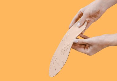 Turuncu bir arka planda ortopedik insole izole edildi. Tıbbi tabanlar. Düz taban ve ayak hastalıklarının tedavisi ve önlenmesi. Ayak bakımı, ayak rahatlığı. Rahat ayakkabılar giy. Düz Ayak Düzeltme