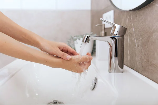 Πλένεις τα χέρια σου κάτω από τη βρύση. Υγιεινή έννοια λεπτομέρεια χέρι. Πλένει τα χέρια τρίβοντας με σαπούνι για την πρόληψη του ιού του στέμματος, υγιεινή για να σταματήσει η εξάπλωση του ιού του στέμματος στο δωμάτιο ή δημόσια πλυντήρια — Φωτογραφία Αρχείου