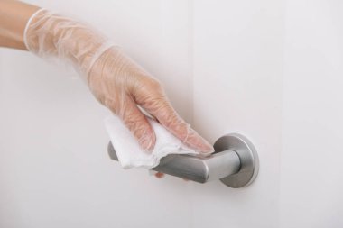 Islak mendil ve beyaz eldivenlerle kapı kolları. Hastane ve kamusal alanlarda korona virüsüne karşı korunma yüzeylerini sterilize edin. Kadın eli temizlik için havlu kullanıyor.