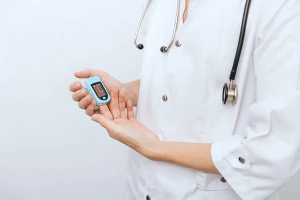 Pulse oximeter with hand of doctor isolated on white. Measuring oxygen saturation, pulse rate and oxygen levels. The concept of portable digital device to measure persons oxygen saturation — Stock Photo, Image