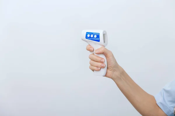 Temperature measurement gun in doctor hands. Close-up shot of doctor wearing protective surgical mask ready to use infrared isometric thermometer gun to check body temperature for virus symptoms — Stock Photo, Image