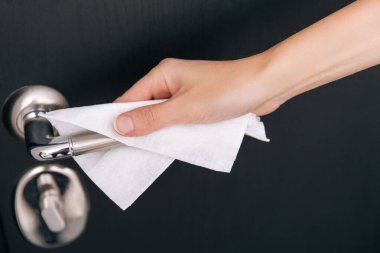 Siyah kapı kollarını antiseptik ıslak mendille temizliyorum. Hastane ve kamusal alanlarda korona virüsüne karşı korunma yüzeylerini sterilize edin. Kadın eli temizlik için havlu kullanıyor.