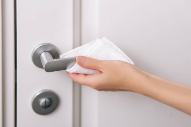 Antiseptik ıslak mendil ve eldivenle kapı kolları temizleniyor. Ev kapısı bağlantısını temizlemek için havlu kullanan kadın eli. Hastane ve halka açık alanlarda korona virüsüne karşı yüzeylerin sterilize edilmesi