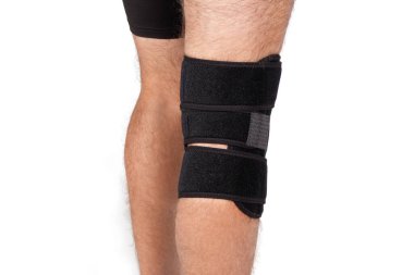 Diz Destek Kolu beyaz arka planda izole edilmiş bir bacak üzerinde. Ortopedik Anatomik. Diz sabitleme, yaralanma ve ağrı için diş telleri. Diz eklemi bandaj kolu. Elastik Spor