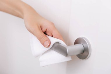 Antiseptik ıslak mendil ve eldivenle kapı kolları temizleniyor. Hastane ve kamusal alanlarda korona virüsüne karşı korunma yüzeylerini sterilize edin. Kadın eli temizlik için havlu kullanıyor.