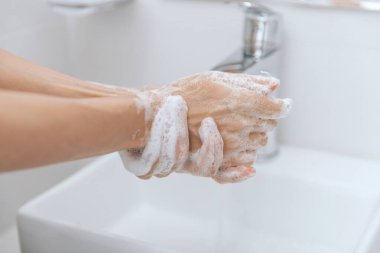 Akan su musluğunun altında ellerini yıkamak. Hijyen konsepti el detayı. Corona virüsünün önlenmesi için sabunla ellerini ovuşturmak, korona virüsünü halka yaymayı durdurmak için hijyen. Ya da umumi tuvalette.