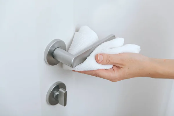 Cleaning black door handles with an antiseptic wet wipe. Sanitize surfaces prevention in hospital and public spaces against corona virus. Woman hand using towel for cleaning — Stock Photo, Image