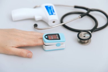 Stetoskop, nabız oksimetresi ve beyaz arka planda termometre tabancası. Phonendoskop. Vücut ısısını kontrol etmek için kızılötesi izometrik termometre tabancası. Soğuk algınlığı veya grip tedavisi