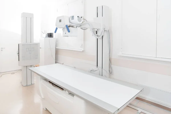 Röntgenabteilung in einem modernen Krankenhaus. Radiologie-Raum mit Scanner mit leerem Bett. Techniker justieren ein Röntgengerät. Brust, Herz und Lungen in moderner Klinik-Praxis abtasten — Stockfoto