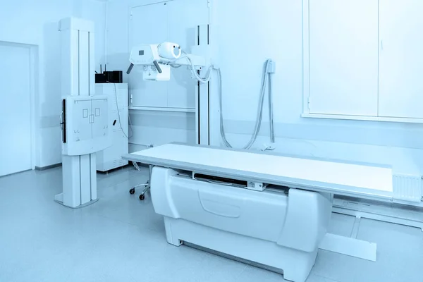 Dział rentgenowski w nowoczesnym szpitalu. Pokój radiologiczny z skanerem z pustym łóżkiem. Technik dopasowuje rentgen. Skanowanie klatki piersiowej, serca, płuc w nowoczesnym gabinecie kliniki — Zdjęcie stockowe