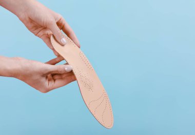 Mavi bir arkaplanda ortopedik insole izole edildi. Tıbbi tabanlar. Düz taban ve ayak hastalıklarının tedavisi ve önlenmesi. Ayak bakımı, ayak rahatlığı. Rahat ayakkabılar giy. Düz Ayak Düzeltme