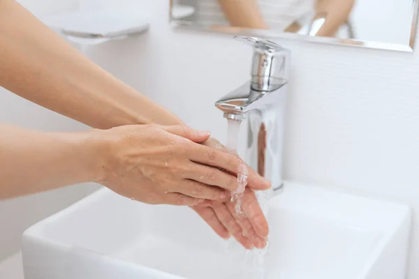 बहते पानी के नल के नीचे हाथ धोना। स्वच्छता अवधारणा हाथ विस्तार। कोरोना वायरस रोकथाम के लिए साबुन से हाथ धोना, या सार्वजनिक वॉश रूम में कोरोना वायरस फैलाने से रोकने के लिए स्वच्छता — स्टॉक फ़ोटो, इमेज