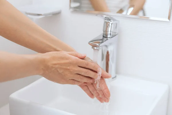 Lavarse las manos bajo el grifo de agua corriente. Concepto de higiene detalle de la mano. Lavarse las manos frotándose con jabón para prevenir el virus de la corona, higiene para dejar de propagar el virus de la corona en el baño público — Foto de Stock