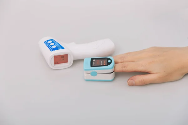 Pulse oximeter and thermometer gun on white background. Infrared isometric thermometer gun to check body temperature for virus symptoms. Measuring oxygen saturation, pulse rate and oxygen levels — Stock Photo, Image