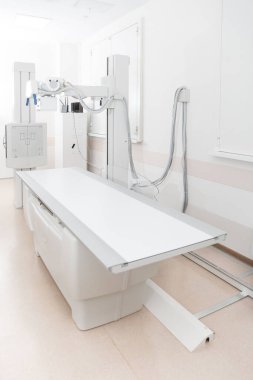 Modern hastanenin röntgen bölümü. Boş yataklı tarama makineli radyoloji odası. Teknisyen röntgen cihazını ayarlıyor. Modern klinikte göğüs, kalp ve akciğerler taranıyor.