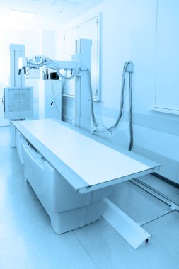 Modern hastanenin röntgen bölümü. Boş yataklı tarama makineli radyoloji odası. Teknisyen röntgen cihazını ayarlıyor. Modern klinikte göğüs, kalp ve akciğerler taranıyor.