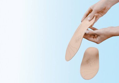 Mavi bir arkaplanda ortopedik insole izole edildi. Tıbbi tabanlar. Düz taban ve ayak hastalıklarının tedavisi ve önlenmesi. Ayak bakımı, ayak rahatlığı. Rahat ayakkabılar giy. Düz Ayak Düzeltme