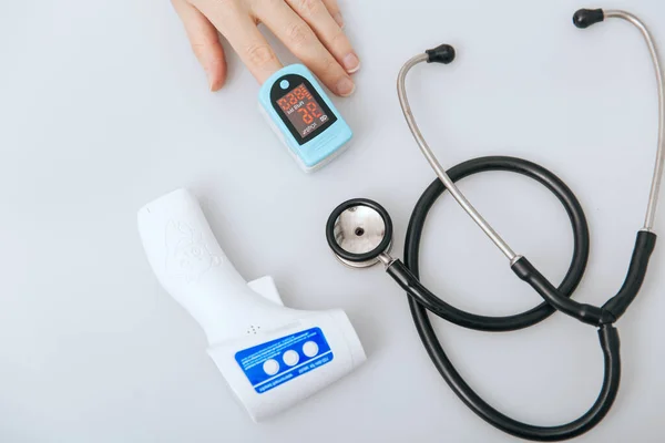 Stethoscope, pulse oximeter and thermometer gun on white background. Phonendoscope. Infrared isometric thermometer gun to check body temperature for virus symptoms. Treatment of cold or flu — Stock Photo, Image