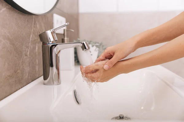 Lavarse las manos bajo el grifo de agua corriente. Concepto de higiene detalle de la mano. Lavarse las manos frotándose con jabón para prevenir el virus de la corona, higiene para dejar de propagar el virus de la corona en el baño público — Foto de Stock