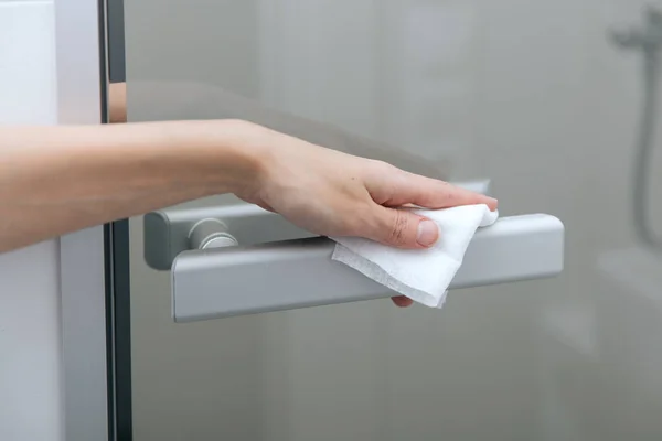 用防腐剂湿擦拭清洗玻璃门把手.在医院和公共场所清洁表面，防止感染日冕病毒。女用手巾清洁家居门链 — 图库照片
