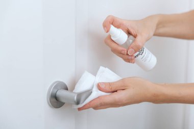 Beyaz kapı kollarını antiseptik ıslak mendil ve dezenfektanla temizliyorum. Hastane ve halka açık alanlarda Corona virüsüne karşı dezenfeksiyon. Kadın eli temizlik için havlu kullanıyor.