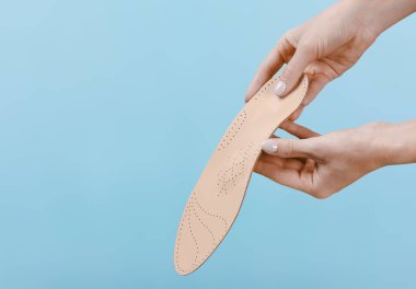 Mavi bir arkaplanda ortopedik insole izole edildi. Tıbbi tabanlar. Düz taban ve ayak hastalıklarının tedavisi ve önlenmesi. Ayak bakımı, ayak rahatlığı. Rahat ayakkabılar giy. Düz Ayak Düzeltme