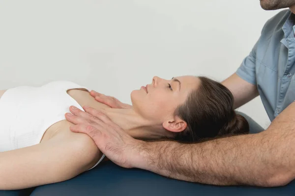 Paziente donna in trattamento osteopatico al collo e alle spalle. Un terapista che manipola la nuca e il torace. Una ragazza in terapia CST. Manipolazione osteopatica e terapia — Foto Stock