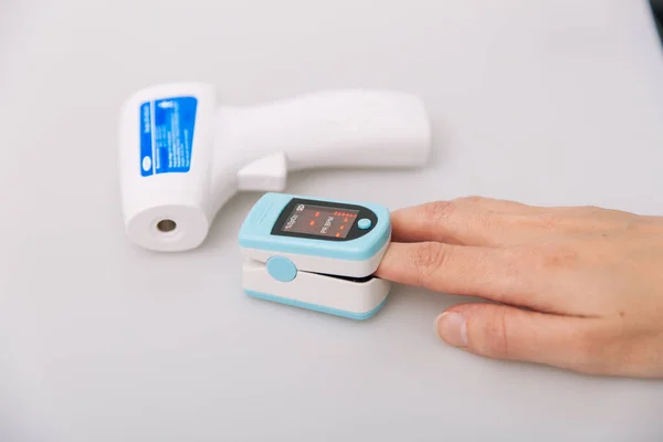 Pulse oximeter and thermometer gun on white background. Infrared isometric thermometer gun to check body temperature for virus symptoms. Measuring oxygen saturation, pulse rate and oxygen levels — Stock Photo, Image