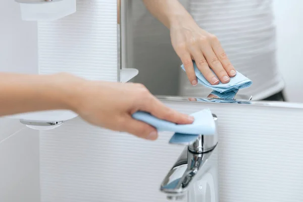 Reinigung des Spülwasserhahns mit einem Mikrofasertuch. Prävention von Oberflächen in Krankenhäusern und öffentlichen Räumen gegen Coronavirus sanieren. Frauenhand mit Feuchttüchern. Reinigung des Badezimmers — Stockfoto