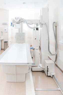 Modern hastanenin röntgen bölümü. Boş yataklı tarama makineli radyoloji odası. Teknisyen röntgen cihazını ayarlıyor. Modern klinikte göğüs, kalp ve akciğerler taranıyor.
