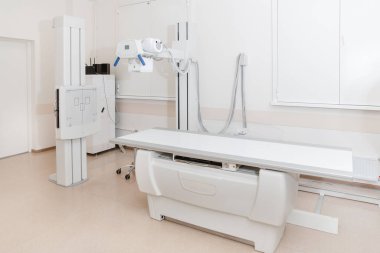 Modern hastanenin röntgen bölümü. Boş yataklı tarama makineli radyoloji odası. Teknisyen röntgen cihazını ayarlıyor. Modern klinikte göğüs, kalp ve akciğerler taranıyor.