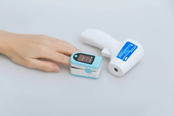 Pulse oximeter and thermometer gun on white background. Infrared isometric thermometer gun to check body temperature for virus symptoms. Measuring oxygen saturation, pulse rate and oxygen levels — Stock Photo, Image