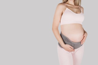 Hamilelik öncesi hamilelik kemeri takmış hamile bir kadın. Ortopedik karın desteği bel, sırt, karın bandı. Hamilelik için karın korsesi ya da bant. Yatay web pankartı. Hamile modelin gövdesi