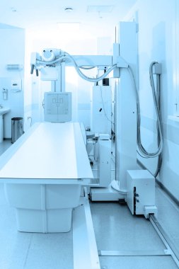 Modern hastanenin röntgen bölümü. Boş yataklı tarama makineli radyoloji odası. Teknisyen röntgen cihazını ayarlıyor. Modern klinikte göğüs, kalp ve akciğerler taranıyor.