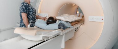 Tomografi tomografisi ya da hastanede MRI taraması olan doktor, hemşire ve hasta. Radyografi bölümünün içi. Beyaz odada teknolojik olarak gelişmiş ekipmanlar var. Manyetik rezonans tanılama makinesi