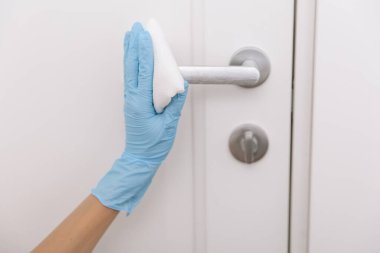 Siyah kapı kollarını antiseptik beyaz mendil ve dezenfektanla temizliyorum. Hastane ve kamusal alanlarda korona virüsüne karşı korunma yüzeylerini sterilize edin. Kadın eli temizlik için havlu kullanıyor.