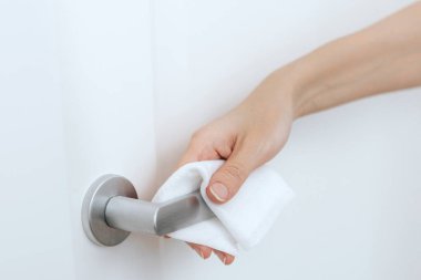 Antiseptik ıslak mendil ve eldivenle kapı kolları temizleniyor. Hastane ve kamusal alanlarda korona virüsüne karşı korunma yüzeylerini sterilize edin. Kadın eli temizlik için havlu kullanıyor.
