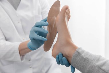 Doktor elleri ortopedik tabanı tutuyor. Ortopedist tıbbi cihazı test ediyor. Beyaz arka planda ortopedik tabanlar. Ayak bakımı, ayaklara iyi gelir. Düztaban ve ayağın tedavisi ve önlenmesi